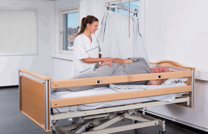 A profiling bed in a hospital – there is a man in the man with a nurse close by