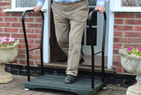 A man coming out of his front door and stepping onto the Bigfoot Half Step which has two handles in place