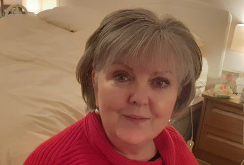 A close up of Lesley, who is wearing a red top and looking towards the camera