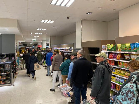 the image shows a socially distant queue in a supermarket