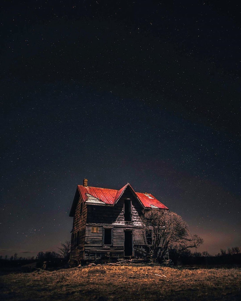 abandoned house in middle of empty field at night