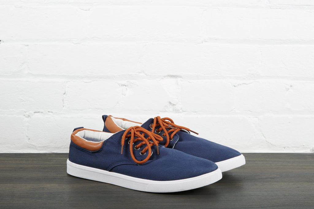 Dark blue, low-top shoes with a white midsole, brown lace, black back tab, and white lining.