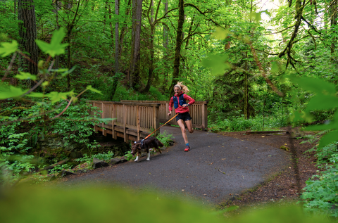 Dog and lady running in woods