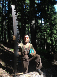 man standing next to crosscut saw