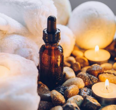 Amber bottle of essential oil with tea lights glowing