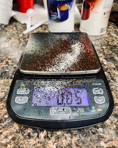 The Truweigh Wave digital washdown scale sits on a granite counter and has coffee grounds and sugar spilled across it.