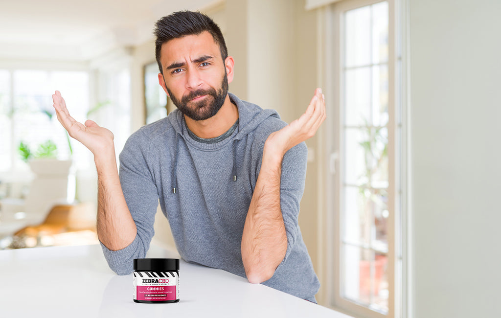 man gesturing in wonder and jar of cbd gummies