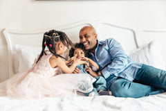 Reduce stress by sleeping better: Father playing with his kids on a bed