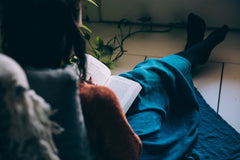A woman sits comfortably on the floor reading a book ready for her hypnotherapy session