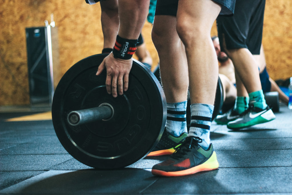 Een man die een plaat met gewicht op een barbell doet