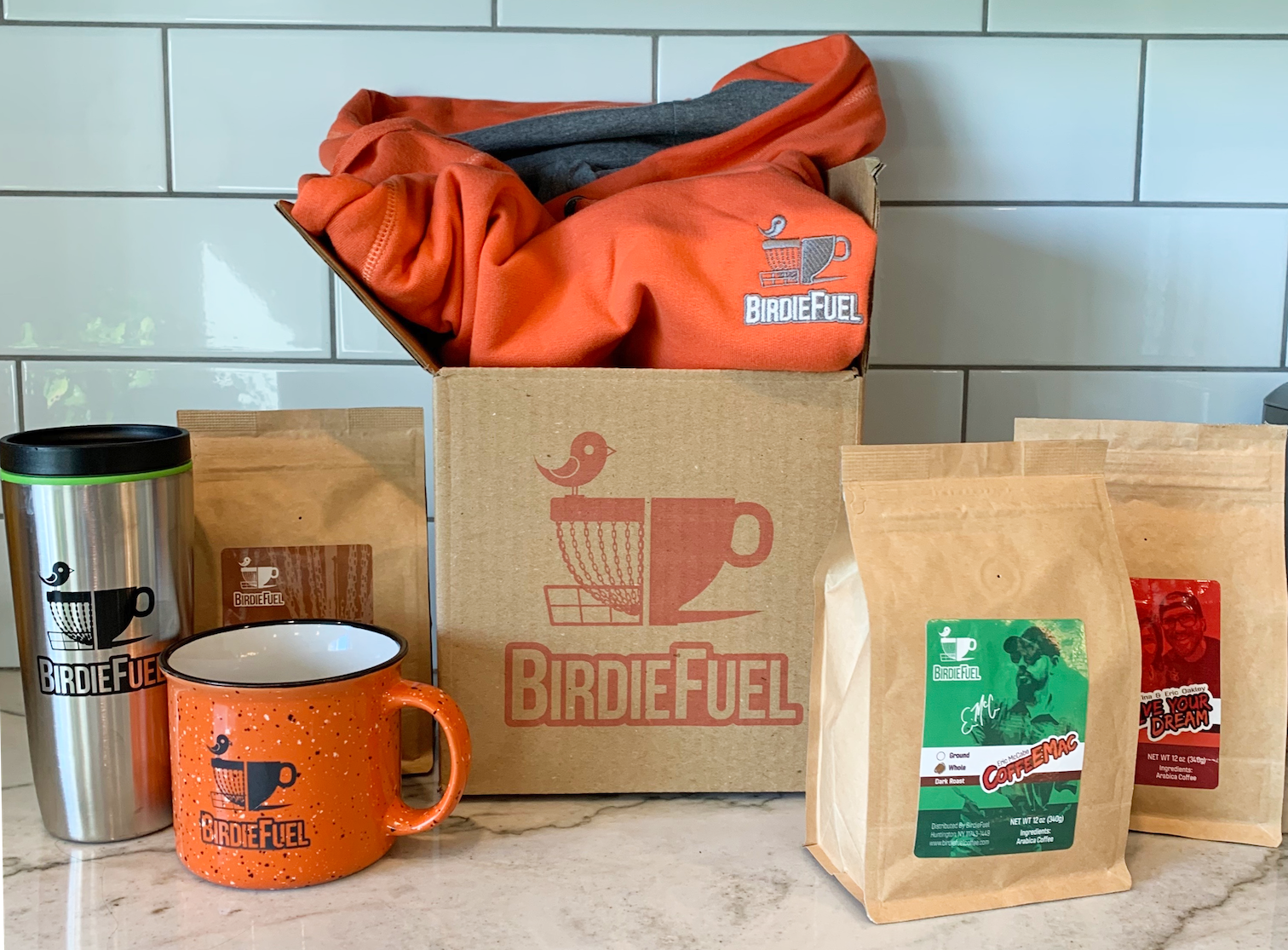 kraft brown shipping box with orange logo next to coffee cup and coffee