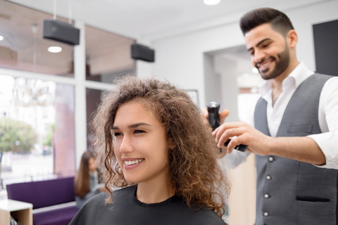 Parrucchiere taglia i capelli di cliente riccia 