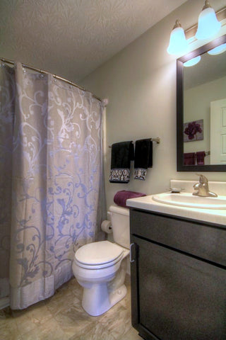 A beautiful bathroom at 300 At The Circle apartment community in Lexington, Kentucky, featuring Rotator Rod: The Curved Shower Rod that Rotates.