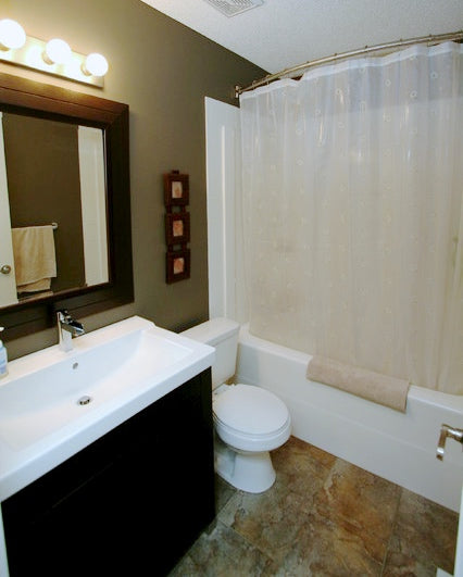 small dark bathroom with slate tile, curved shower rod, small shower/bathtub combination, semi-transparent shower curtain... 5 Steps to Make Your Small Shower Look Bigger Without Remodeling from Bathroom Bliss by Rotator Rod 