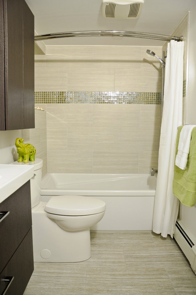 small beige bathroom with curved shower curtain rod, striped tile, green and white accents, dark cabinetry... 5 Steps to Make Your Small Shower Look Bigger Without Remodeling from Bathroom Bliss by Rotator Rod 