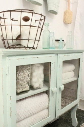 beautiful guest bathroom detail of mint green cabinet with glass doors, fluffy towels and other essentials... Prepare for Holiday House Guests with a Well Stocked Guest Bathroom from The Bathroom Bliss Blog by Rotator Rod