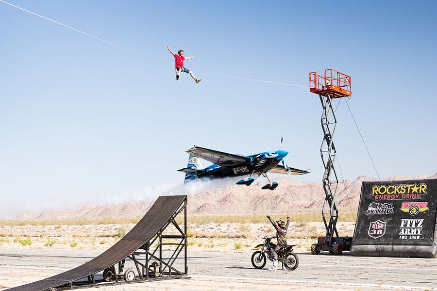 Stunt photo with tightrope walker, dirt bike, and airplane