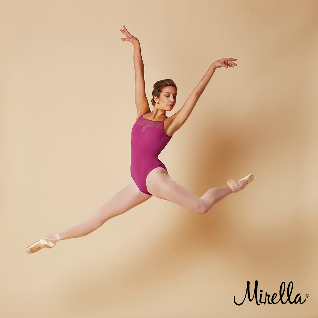 Ballet dancer Sasha Mukhamedov leaping through the air wearing the Mirella open back lace camisole leotard in tulip pink with pink tights and pointe shoes 