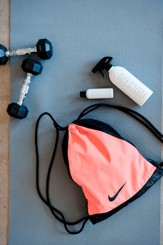 weights, gym bag and stretch spray over a yoga matt