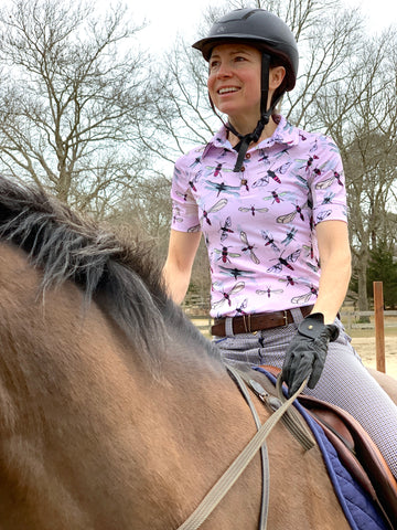 Woman on a horse wearing short sleeve sun shirt polo with UPF or SPF protection and pink flying insects design