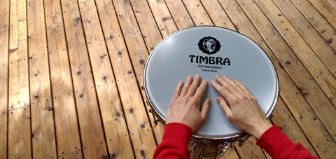 Timbal or timbau made by timbra, with hands on a wooden deck.