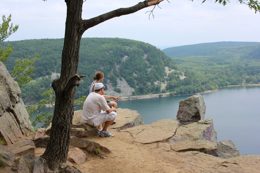 man sitting on rock next to woman pointing to Devil's Lake