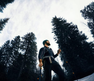 man with trekking poles sidehilling in winter