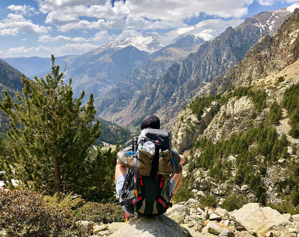 backpacker sitting on rock overlooking mountain range
