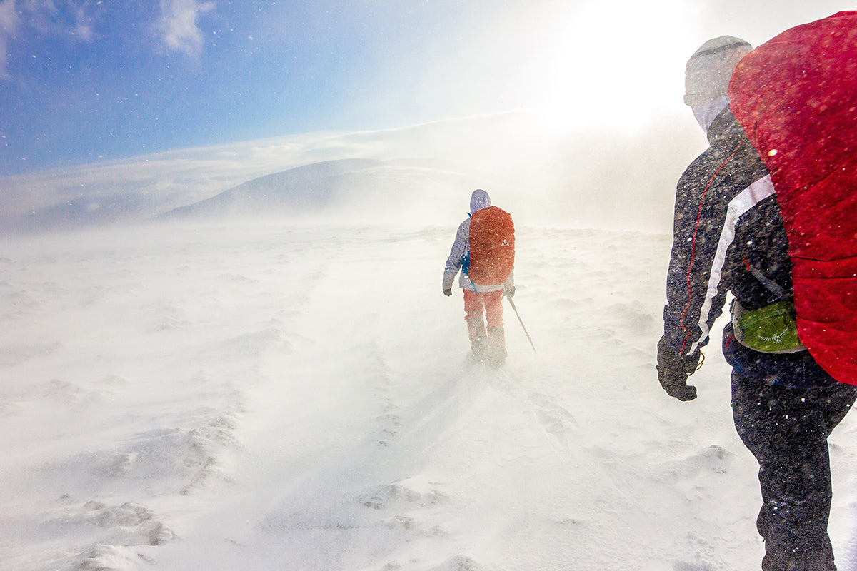 two people walking in snow under blue sky
