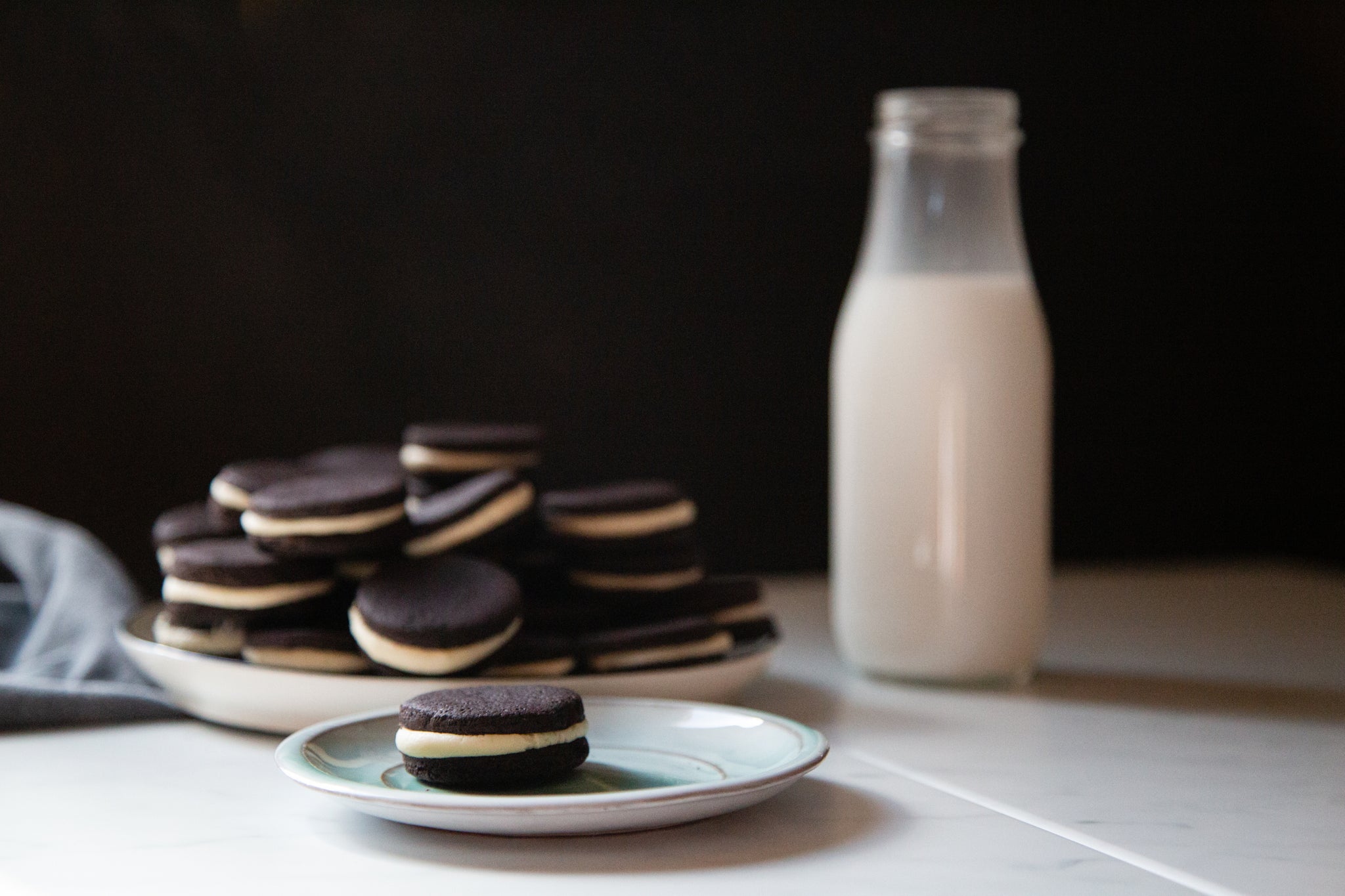 homemade oreo cookies with jar of milk on the side made using black velvet cacao powder by weirdo good