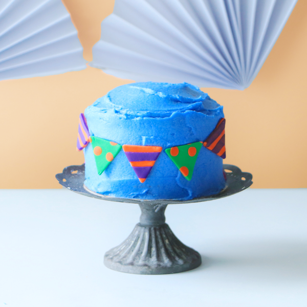 Polka dot and striped bunting on a blue mini cake.