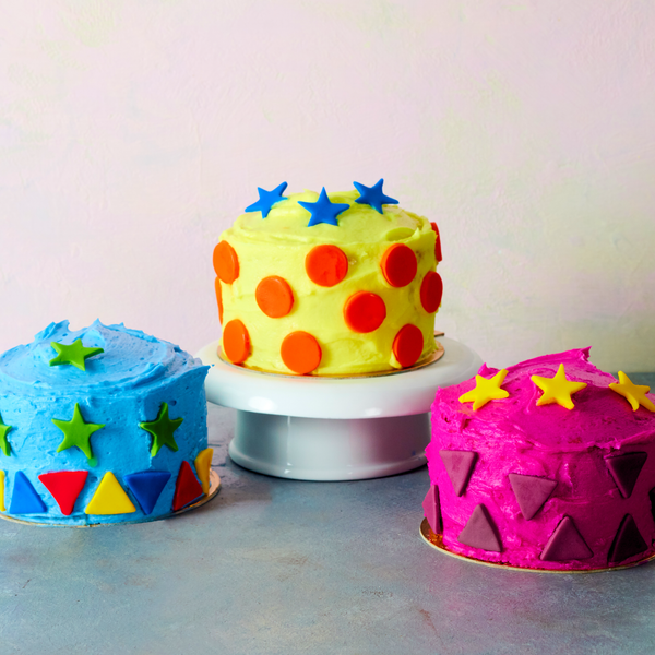 Three mini cakes, decorated with colored buttercream and fondant cut outs.