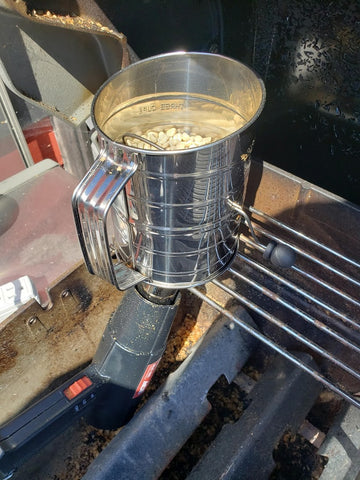 Roasting coffee inside a flour sifter, with a hot air gun underneath.