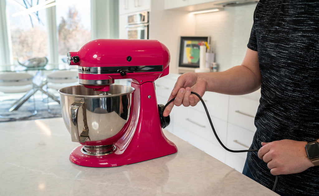 man wrapping cord around electric cord organizer in kitchen