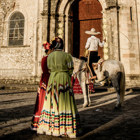 Photo by Pablo Rebolled - a vaquero on horse with a reata and 2 women in traditional Mexican clothes observing him