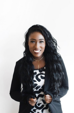 Woman in sustainability with black blazer against a white wall