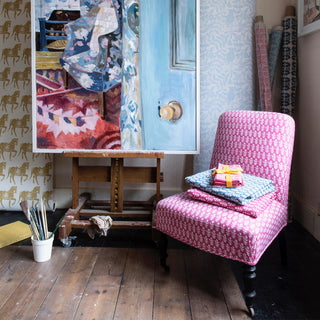 Molly Mahon Bagru pink design fabric upholstered on an armchair sat next to a oil painting