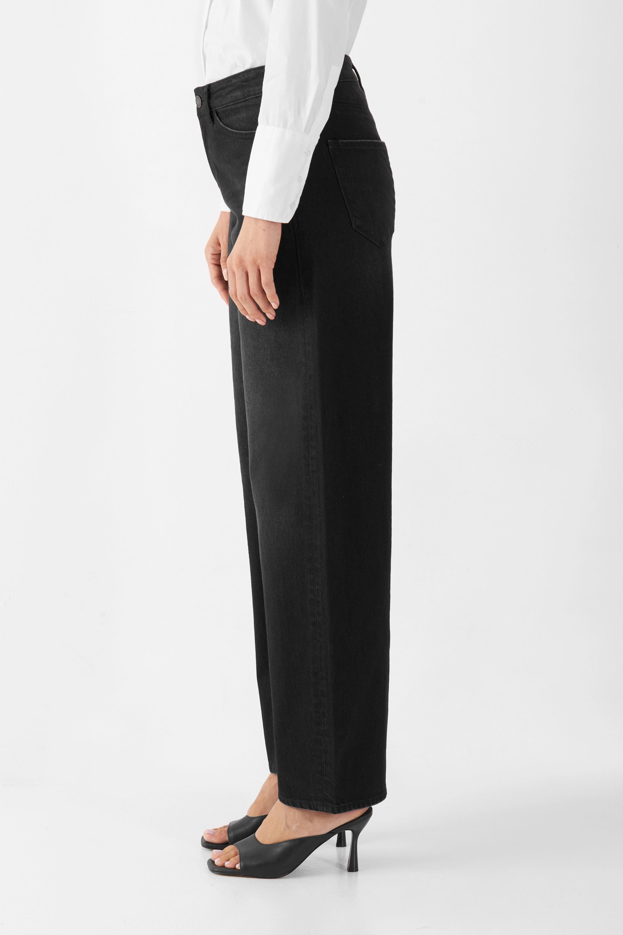 Seitliche Ansicht einer schwarzen Barrel-Leg Jeans (5-Pocket), mittlere Taille, weite Oberschenkel, zum Saum hin schmaler, Minimal-Stretch.