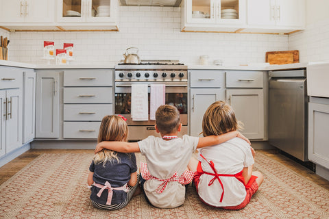 three kids sitting in front of oven waiting for homemade chocolate chip cookies