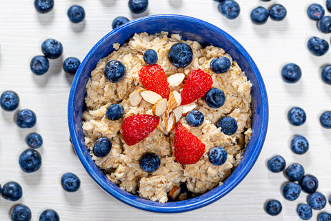 Top view oatmeal porridge with blueberries, almonds and strawberries