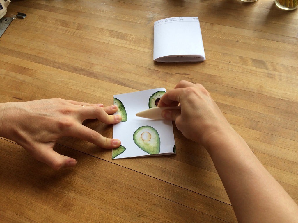 hands folding paper in half with paper creaser