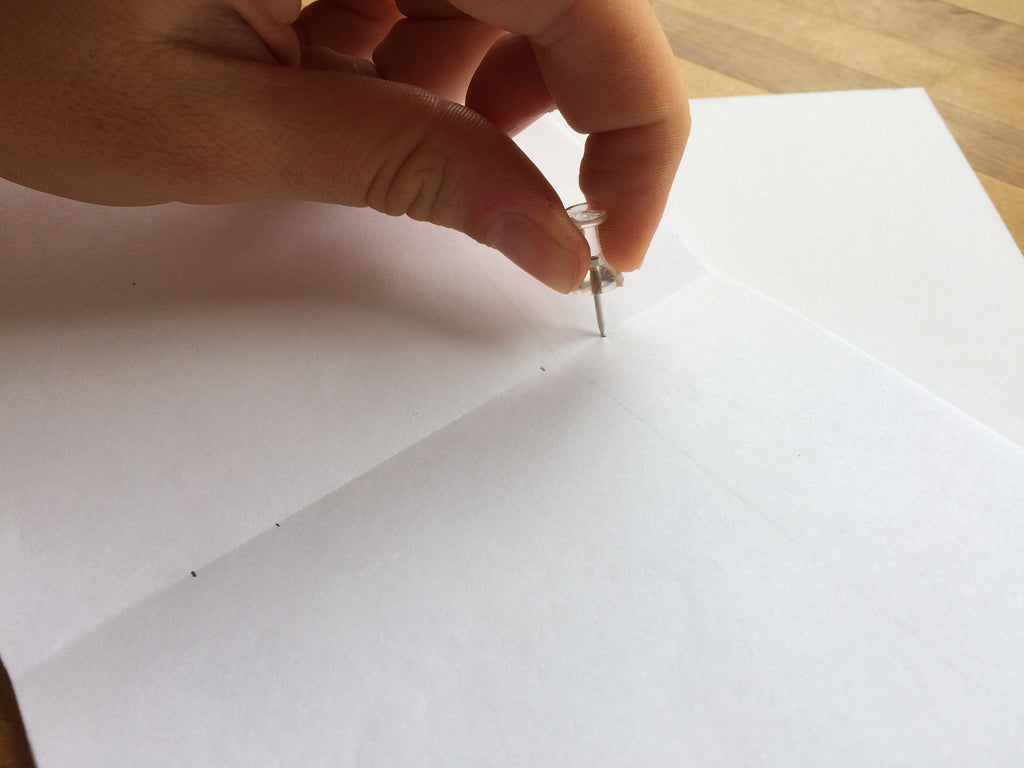pushpin going through a stack of paper 