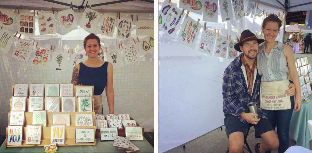 Man and woman at farmers market selling their watercolor illustrations and cards