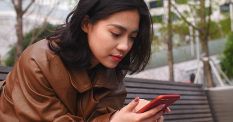 woman holding phone and viewing a mental health mobile app