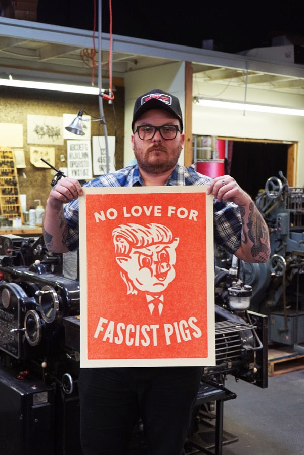 Printmaker Carl Carbonell holding his art "No Love For Fascist Pigs"
