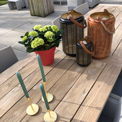 Mooie accessoires op je tuintafel: windlichten, kaarsen in kandelaars en een gezellige plant
