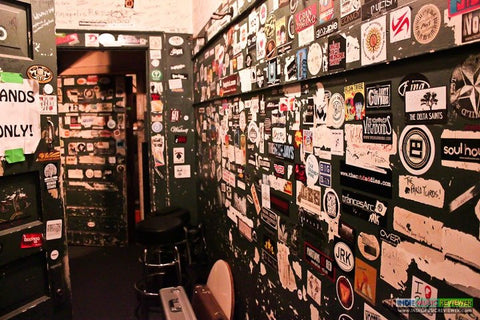 backstage in band prep room at a venue - wall covered in band stickers