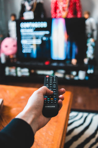 Male Hand Holding a Remote Control Pointing at a TV