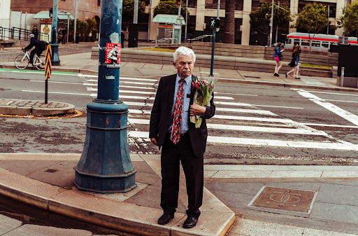 old man standing with a bouquet of roses in hand