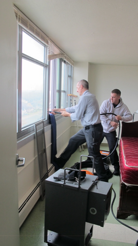 Pest control professionals lowering power cables from the 29th floor of a high rise residential apartment down to the self-contained power truck and electric bed bug heaters.